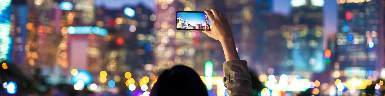 person taking a photograph of a city skyline at night