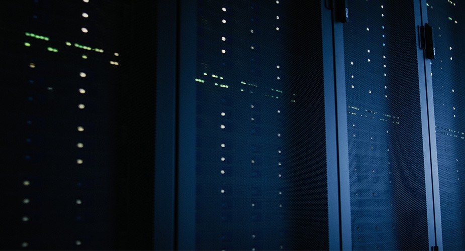 row of lit-up server banks in a dark data center
