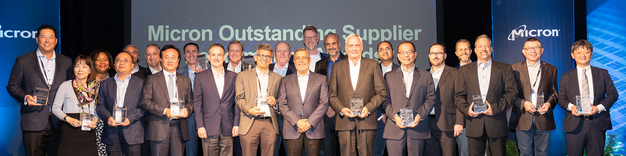Group of Micron employees posing with an award along with the CEO at the center