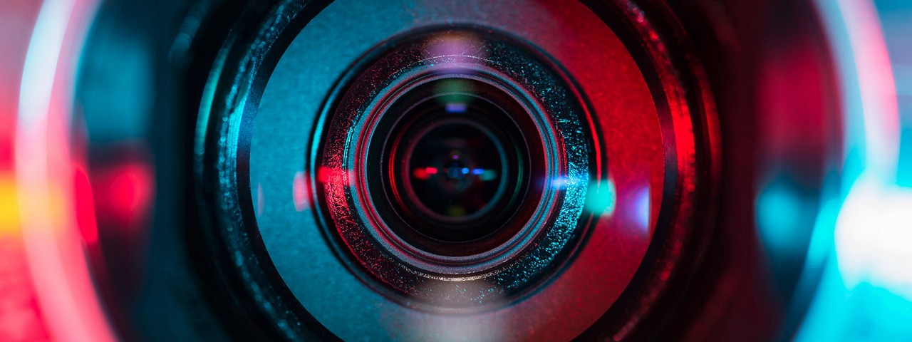 Closeup of a camera lense with a red to purple gradient overlay.