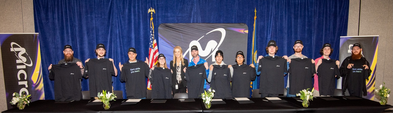 hero_211113-micron-0021-2000x500.jpg: picture of 12 Micron apprentices in front of blue drape